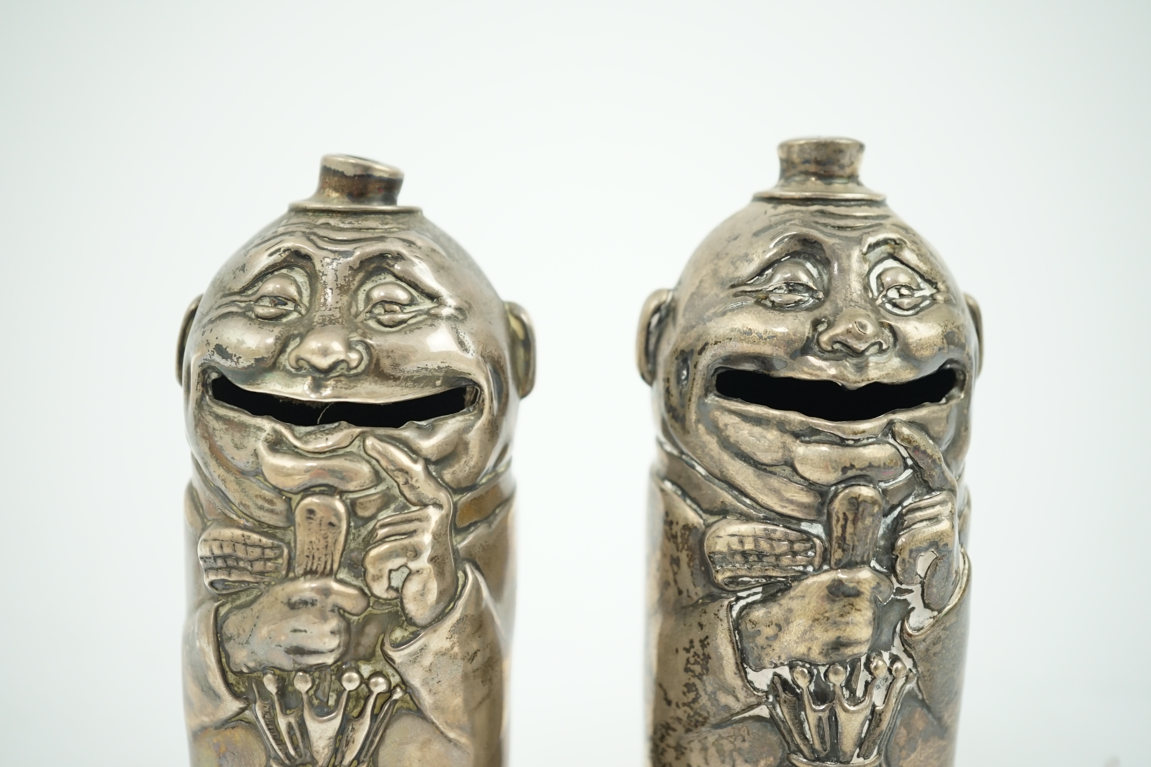 A matched pair of George V novelty silver money boxes, each cylindrical box embossed as a banker with an umbrella, the circular base inscribed 'Always be prepared for a rainy day'